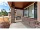 Inviting front porch with swing, brick pillars, and beautifully landscaped surroundings at 5540 Palomino Way, Frederick, CO 80504