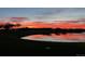 Scenic pond view reflecting a vibrant red and orange sunset with mature trees in the community at 16323 River Haven Way, Morrison, CO 80465