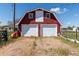 Front view of a red barn with white garage doors and a dirt front at 14347 E 134Th Ave, Brighton, CO 80601