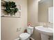 Powder room featuring pedestal sink, toilet, and decorative wall art at 15145 W Washburn Ave, Denver, CO 80228