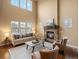 Bright living room featuring a fireplace, a high ceiling, and a staircase at 15145 W Washburn Ave, Denver, CO 80228