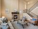 Bright living room featuring a cozy stone fireplace and a staircase with iron railings at 15145 W Washburn Ave, Denver, CO 80228