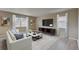 Cozy living room featuring a sleek entertainment unit, comfortable seating, and bright, natural light from the windows at 20040 E 61St Dr, Aurora, CO 80019