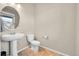 Clean powder room with a pedestal sink, round mirror, and neutral color scheme at 20040 E 61St Dr, Aurora, CO 80019