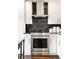 Close-up of a modern kitchen with stainless steel oven, black subway tile backsplash, and white cabinets at 1700 Bassett St # 314, Denver, CO 80202