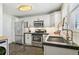 Modern kitchen with stainless steel appliances, white cabinets, and a stone countertop at 2441 E 47Th Ave, Denver, CO 80216