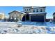 Two-story home with stone accents and a three-car garage in snowy setting at 15454 W Auburn Ave, Lakewood, CO 80228