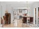 Dining area with modern light fixture that leads to the kitchen with white cabinets and stainless steel appliances at 247 Tipple Pkwy, Frederick, CO 80530