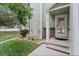 Inviting covered front porch with brick accents and a decorative glass door, surrounded by lush landscaping at 8997 W 88Th Ave, Westminster, CO 80021