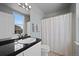 Well-lit bathroom with double vanity, black countertop, and shower with curtain at 12896 Ironstone Way # 203, Parker, CO 80134