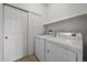 Functional laundry room with washer, dryer, and built-in shelving behind closet doors at 13023 Grant Cir # C, Thornton, CO 80241