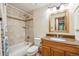 Bathroom featuring tile backsplash, a bathtub with shower, a toilet, and wood cabinets with a granite countertop at 11431 W Lake Dr, Littleton, CO 80127