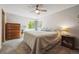 A cozy bedroom featuring a ceiling fan, dresser, nightstand, and a comfortable bed with window view at 11431 W Lake Dr, Littleton, CO 80127