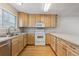 U-shaped kitchen featuring wood cabinets, white appliances, lots of natural light and hardwood floors at 3006 W 107Th Pl # D, Westminster, CO 80031