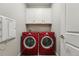 Well-equipped laundry room featuring red front-load washer and dryer with white cabinets at 1592 Maggie Mae Ln, Castle Rock, CO 80104