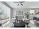 Open-concept living area features a gray sectional, round coffee table, and large window with modern blinds at 1592 Maggie Mae Ln, Castle Rock, CO 80104