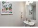 A bright half bathroom featuring a pedestal sink, mirror, light fixture, and artwork at 888 S Valentia St # 14-103, Denver, CO 80247