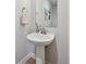 A traditional pedestal sink in a half bathroom complemented by a framed mirror and decor at 888 S Valentia St # 14-103, Denver, CO 80247