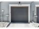 Attached garage with gray door and exterior pebble landscaping at 888 S Valentia St # 14-103, Denver, CO 80247