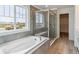 Modern bathroom featuring a soaking tub, glass shower, and large window with ample natural light at 25254 E Warren Pl, Aurora, CO 80018