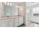 Bright bathroom featuring double sink vanity with a large mirror and glass enclosed shower at 4464 Boone Cir, Brighton, CO 80601