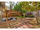 Spacious backyard with a charming brick pathway, mature trees, and a cozy outdoor patio area at 3835 Pecos St, Denver, CO 80211