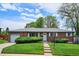 Charming brick home featuring a well-manicured lawn, mature landscaping, and an attached garage at 8490 E Davies Pl, Centennial, CO 80112