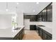 Bright kitchen with dark cabinetry, stainless steel appliances, pendant lights, and a white island at 13342 E 110Th Way, Commerce City, CO 80022
