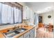Bright kitchen area showcasing light wood floors, double stainless steel sink and a view into the dining area at 3977 S Pitkin Way, Aurora, CO 80013