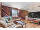 Comfortable living room features wood paneling, hardwood floors, and a large TV for entertainment at 3977 S Pitkin Way, Aurora, CO 80013