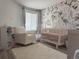 Charming Bedroom with a crib, comfortable chair, and delightful floral wallpaper at 13781 E Lehigh Ave # E, Aurora, CO 80014