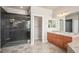 Modern bathroom featuring a glass enclosed shower, wood cabinets, a large mirror and sleek lighting fixtures at 22090 E Arbor Dr, Aurora, CO 80016