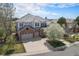 Stunning home exterior with brick accents, three car garage, and a lovely flowering tree at 22090 E Arbor Dr, Aurora, CO 80016