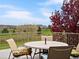 Relaxing back deck with table and chairs offers sweeping views of lush greenery, distant mountains, and bright sky at 16631 Red Cliff Cir, Morrison, CO 80465
