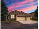 Charming single-story home boasts a three-car garage and beautifully landscaped front yard at sunset at 16631 Red Cliff Cir, Morrison, CO 80465