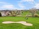 Scenic golf course view features a sand trap, golf cart and players in the distance, highlighting the community's amenities at 16631 Red Cliff Cir, Morrison, CO 80465