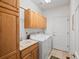 Well-equipped laundry room with modern washer, dryer, built-in cabinets, utility sink, and tile flooring at 16631 Red Cliff Cir, Morrison, CO 80465