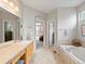 Luxurious bathroom featuring dual sinks, soaking tub, walk-in shower, and view of bright bedroom at 16631 Red Cliff Cir, Morrison, CO 80465