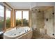 Bright main bathroom with a soaking tub, glass enclosed shower, tile floors, and large windows at 11227 Explorers Run, Littleton, CO 80125