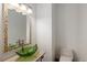 Stylish powder room with decorative mirror, unique leaf-shaped glass sink, and neutral walls at 11227 Explorers Run, Littleton, CO 80125