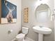 Powder room with pedestal sink, toilet, and decorative wall art at 9876 Ceylon Ct, Commerce City, CO 80022