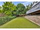 Backyard featuring artificial turf, retaining wall, mature trees and a covered deck at 4678 Springmeadow Ln, Castle Rock, CO 80109