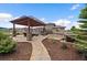 Backyard featuring a pergola with an outdoor kitchen and dining area, a hot tub, stone walkway, and mature trees at 12590 Valentia St, Thornton, CO 80602