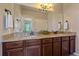 Bathroom with double sinks, granite countertops, and wood cabinetry under a large mirror at 12590 Valentia St, Thornton, CO 80602