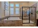 Well-lit bathroom featuring a soaking tub and glass shower with tile surround at 12590 Valentia St, Thornton, CO 80602