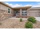 Inviting front porch with stone columns, wooden decking, and landscaping around the base of the house at 12590 Valentia St, Thornton, CO 80602