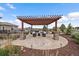 Stone patio and pergola with outdoor dining area, and string lights surrounded by manicured landscaping at 12590 Valentia St, Thornton, CO 80602