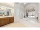 Bright bathroom featuring double sinks, a soaking tub under a large window, and storage at 60 Glenalla Pl, Castle Rock, CO 80108