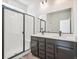 Bright bathroom featuring a double vanity with sleek black hardware and a tiled shower with a glass door at 9265 Cathay Ct, Commerce City, CO 80022