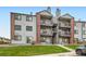 A multi-level condo building featuring grey siding, brick accents, and private balconies on each floor at 10785 W 63Rd Pl # 108, Arvada, CO 80004